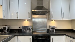 Une cuisine moderne avec des armoires blanches, des appareils en acier inoxydable et un four encastré.