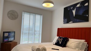 Une chambre à coucher avec un lit, une télévision, une horloge et un tableau.