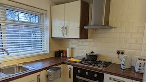 A compact kitchen with a gas stove, oven, and a small sink. - Fully-equipped Flat in the City of London (London)