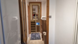 A narrow hallway with wooden doors, a carpeted floor, and a small rug. - Fully-equipped Flat in the City of London (London)