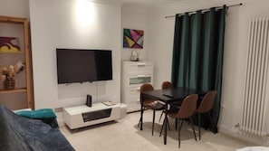 A modern living room with a flat-screen TV, a dining table with chairs, a sofa, and a cabinet. - Fully-equipped Flat in the City of London (London)