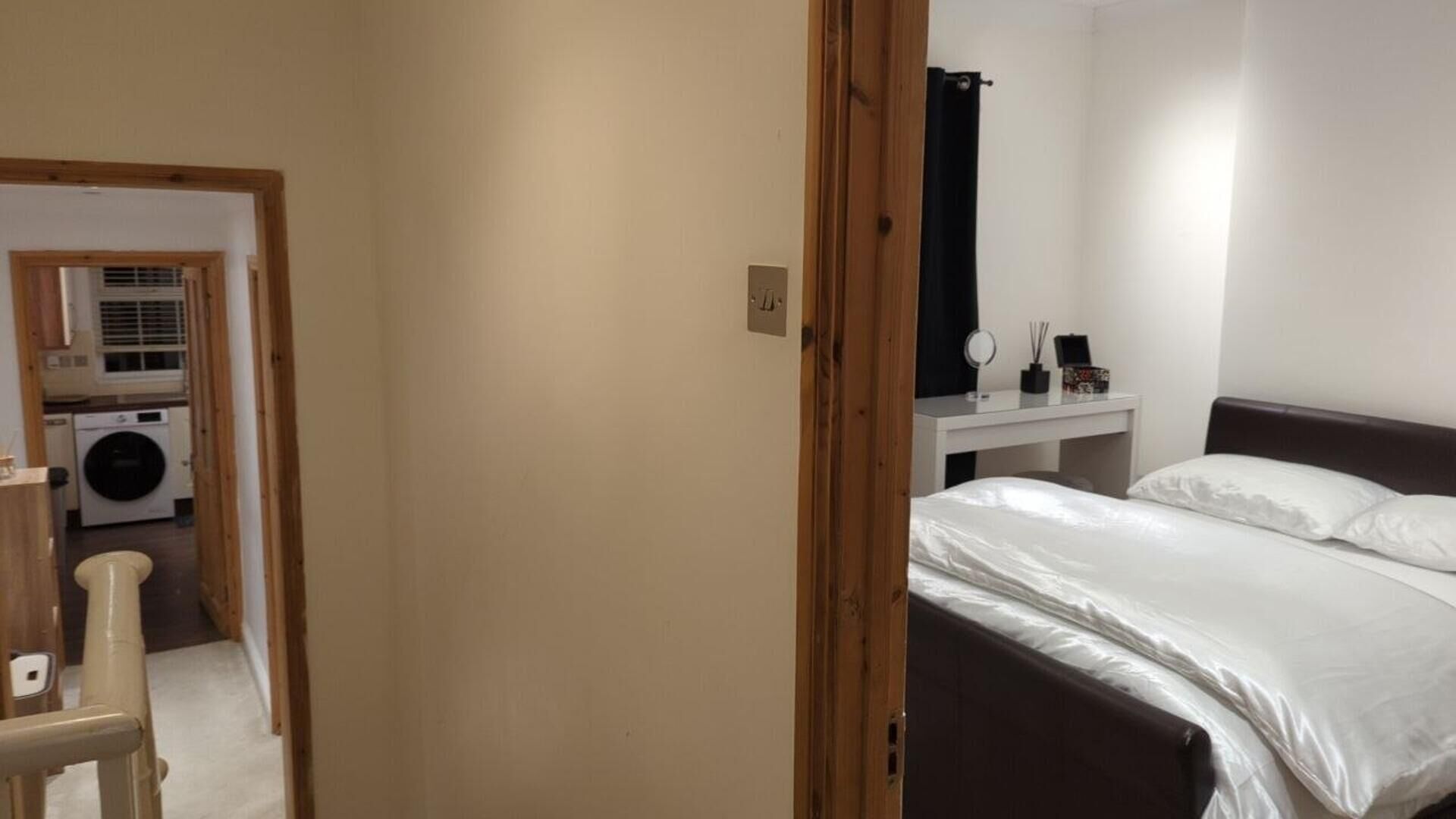 A bedroom with a bed, a bedside table, and a small desk with a mirror.