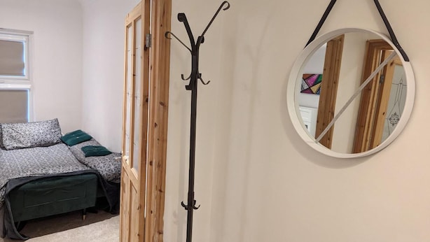 A bedroom with a bed, a coat rack, and a mirror on the wall. - Fully-equipped Flat in the City of London (London)