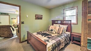 A bedroom with a bed, a wooden headboard, a nightstand, a chair, a ceiling fan, and a window. - Wooded Danbury Cabin w/ Grill + Fire Pit! (Danbury)