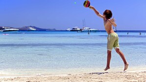 A beach scene with a person playing with a ball, boats in the background, and clear blue water. - Luxury Villa Gaby With Heated Pool (Sali)