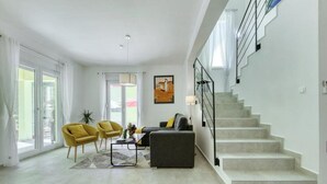 A modern living room with a staircase, large windows, and a painting on the wall. - Luxury Villa Gaby With Heated Pool (Sali)