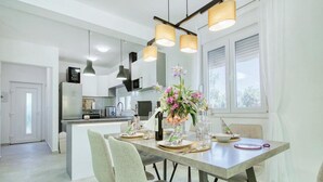 A modern kitchen with a central island, pendant lighting, and a dining area with chairs and a table set for two. - Luxury Villa Gaby With Heated Pool (Sali)