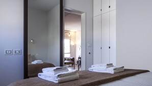 A hotel room with a large bed, a mirror, and a view into the dining area. - Melchett Plume in Tel Aviv-yafo (Tel Aviv)