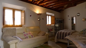 A cozy room with a sofa, a bed, a small table, and a window with curtains.