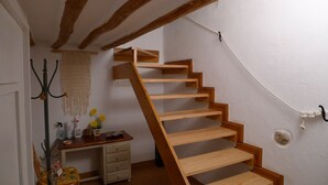 A wooden staircase in a room with a desk, a hanging macrame wall decoration, and a small plant.