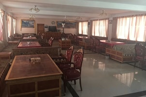 A spacious room with a large dining table, several chairs, a sofa, and a television.