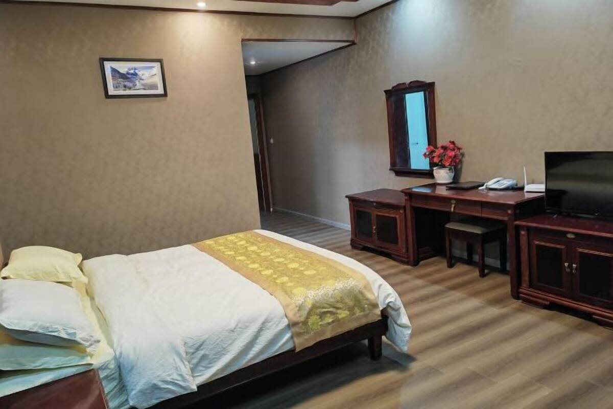A hotel room with a bed, a desk, a chair, a television, and a cabinet.
