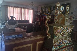 Una habitación con un escritorio de madera, una estantería y un aparador decorativo con diseños intrincados.