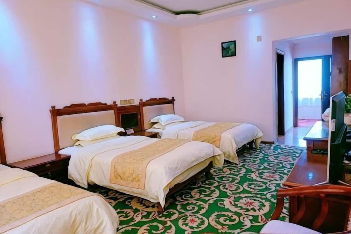 A hotel room with two beds, a desk, and a television.