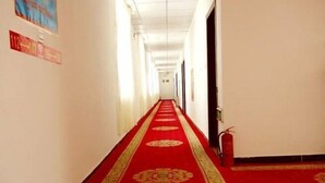 Un couloir avec un tapis rouge et un extincteur sur le côté droit.