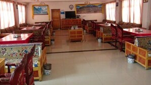Un espace repas comprenant plusieurs tables et chaises, un téléviseur et un tableau accroché au mur.