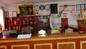 Un espace d’accueil avec un bureau en bois, des étagères contenant divers objets, une horloge, des certificats et un portrait encadré.