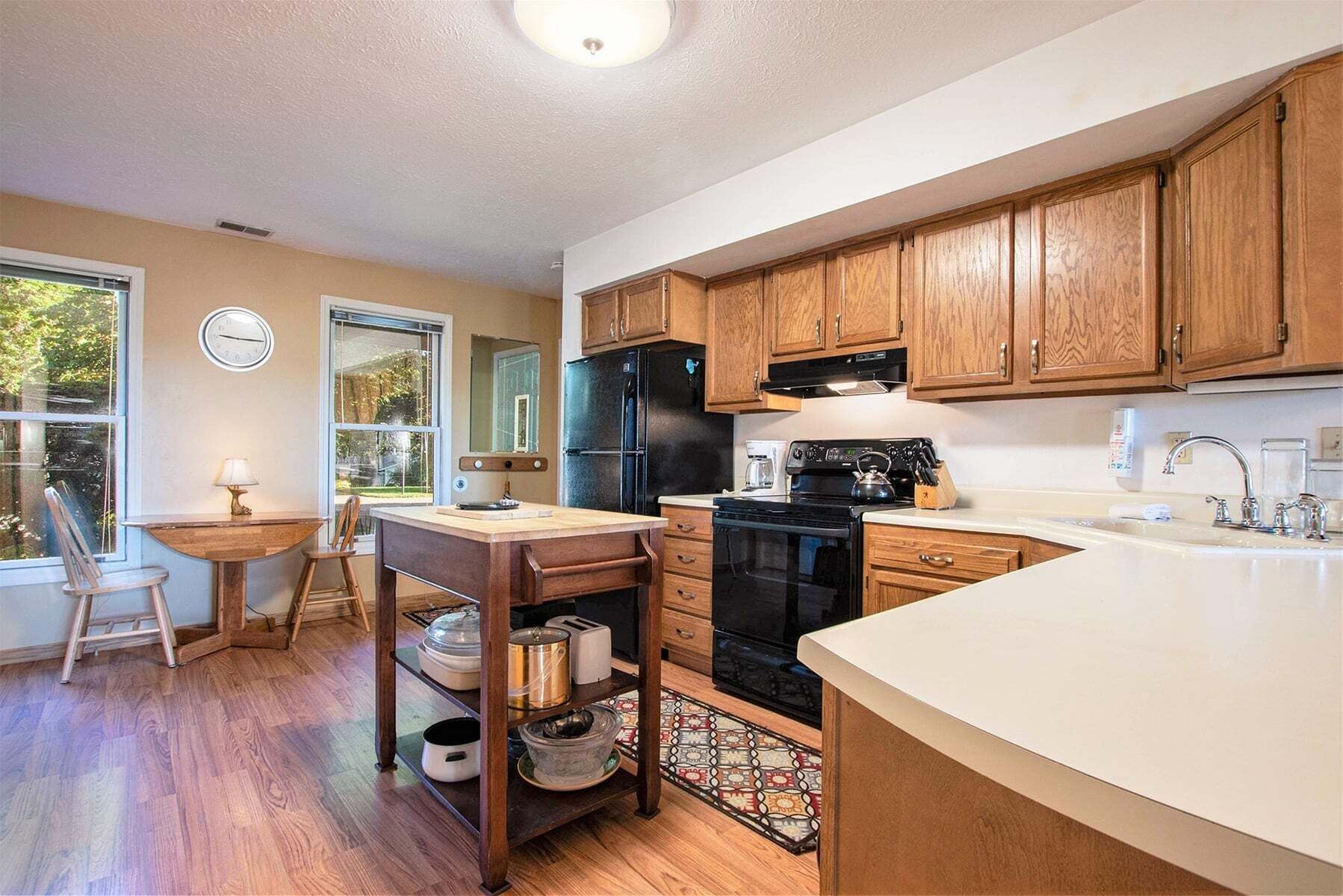 A kitchen with wooden cabinets, a black refrigerator, a stove, and a sink.