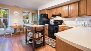 A kitchen with wooden cabinets, a black refrigerator, a stove, and a sink. - Amazing Bayview: Swimming Pool, Harbor Views, Downtown Saugatuck, Balcony (Saugatuck)