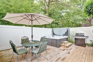 A patio with a table and chairs, a hot tub, and a grill.