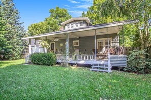 A two-story house with a porch, a small garden, and a wooden fence.