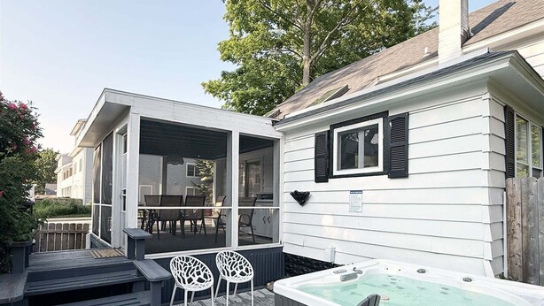 A patio with outdoor seating, a hot tub, and a screened porch.