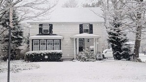 A two-story house with a front porch, a garage, and a snow-covered lawn.