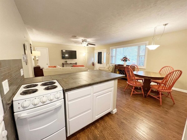 A compact kitchen with a stove, oven, and dining area with chairs and a table.