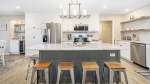Een moderne keuken met een centraal eiland, roestvrijstalen apparatuur en een paar barkrukken.