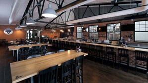 A spacious restaurant with high ceilings, exposed beams, and a long counter with bar stools. - The Old Snow Farm: Lake Allegan Waterfront, Classic Farmhouse, Fire Pit, Patio (Allegan)