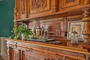 A wooden dresser with intricate carvings, a green plant, and various glassware.