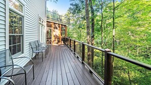 Une terrasse en bois, dotée de chaises, qui offre une vue sur une zone boisée.