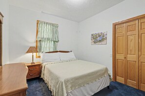 A bedroom with a bed, nightstand, lamp, and a wardrobe. - Great Escape: Spacious, Home Theater, Fire Pit, Walk to Downtown (Saugatuck)