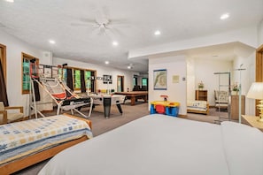 A hotel room with a bed, a desk, a chair, a small table, a ceiling fan, and a window. - Great Escape: Spacious, Home Theater, Fire Pit, Walk to Downtown (Saugatuck)