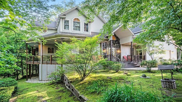 Une maison à deux étages dotée d’un porche abrité, d’une cheminée en pierre et d’un jardin bien entretenu.