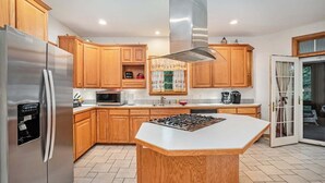 Une cuisine moderne avec des meubles en bois, des appareils électroménagers en acier inoxydable et un îlot central.