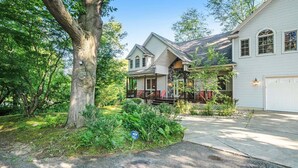 Une maison à deux étages avec une façade en pierre, un porche abrité et un garage.