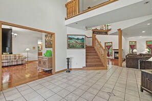 A spacious living area with a wooden staircase, a fireplace, and a painting on the wall.