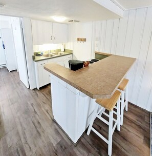 Enjoy cooking in this well-equipped kitchen with a central island, white cabinetry, and a stove.