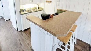 A kitchen with white cabinets, a wooden countertop, and a built-in stove. - Anchors Away: Nautical downtown Saugatuck abode with balcony and partial river views (Saugatuck)
