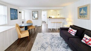 A compact living space with a dining area, kitchen, and a sofa with decorative pillows. - Anchors Away: Nautical downtown Saugatuck abode with balcony and partial river views (Saugatuck)