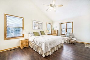 A bedroom with a bed, nightstands, a dresser, a chair, and a ceiling fan.