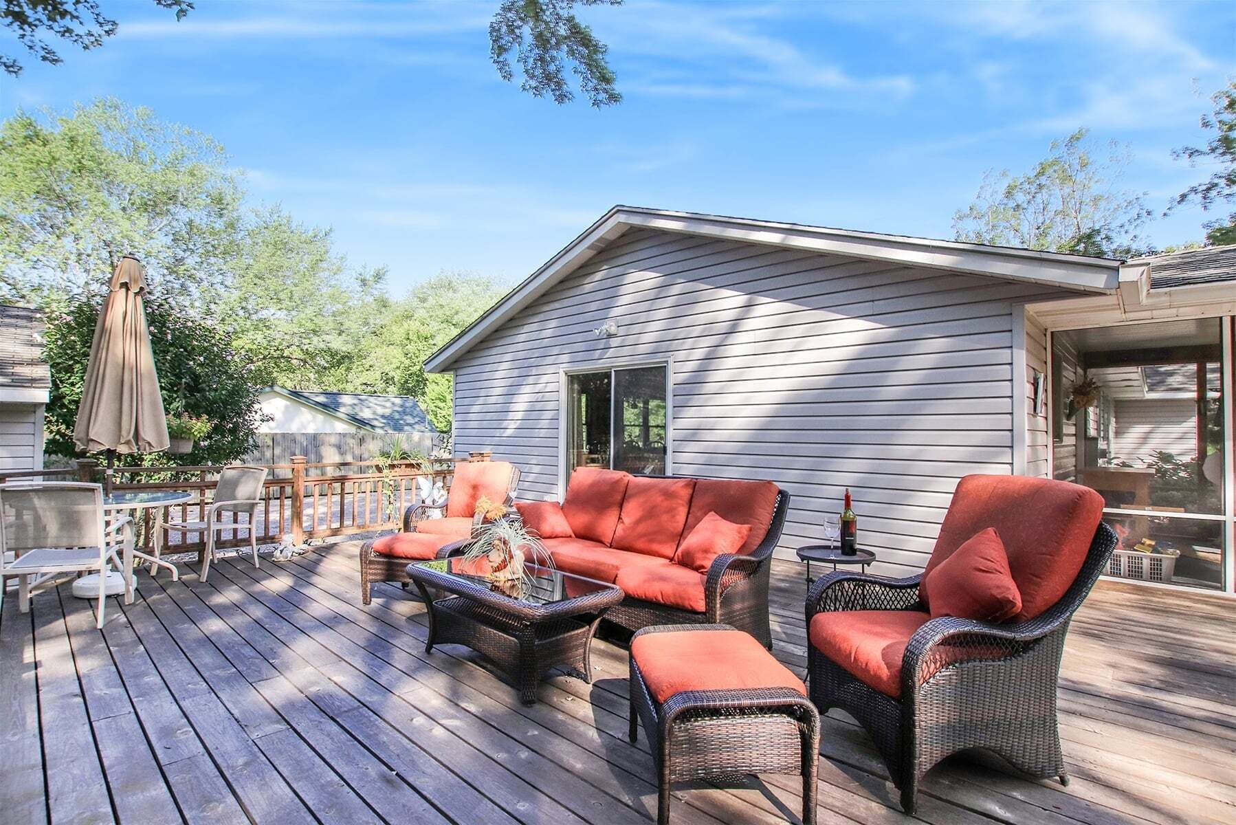 A wooden deck with outdoor furniture, including a sofa and chairs, and a small table.