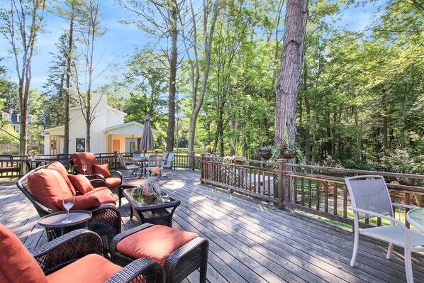 A wooden deck with wicker furniture, a small table, and a chair.