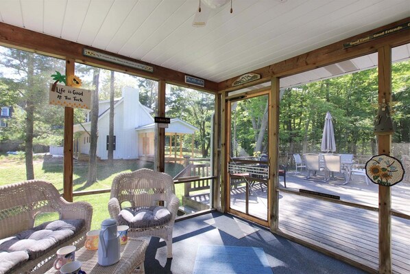 A covered patio with wicker furniture, a coffee table, and a sign that reads 'Life is Good At The Tuck.'