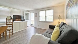 A living room with a sofa, a television, and a dining area with a table and chairs.
