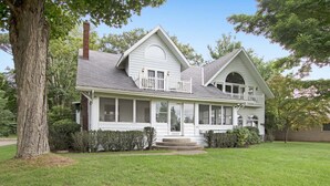 A two-story house with a porch, a chimney, and a well-maintained lawn.