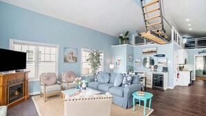 Ein geräumiges Wohnzimmer mit Kamin, Fernseher und einer Treppe, die in einen oberen Bereich führt.