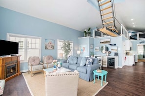 A spacious living room with a fireplace, a television, and a staircase leading to an upper level.