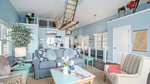 Ein Wohnzimmer mit blauer Wand, einer Holzleiter, einem Sofa, einem Couchtisch und einem Sessel.